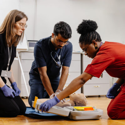 Diverse group of medical students practicing cpr on a medical manikin during first aid training in a hospital or clinic setting